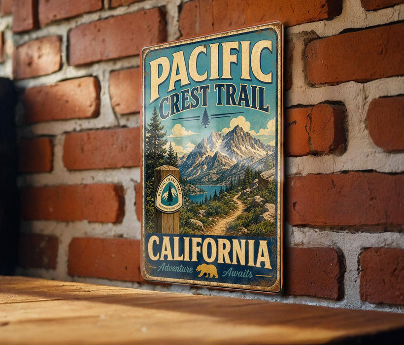 A vintage metal sign for the Pacific Crest Trail in California, featuring a scenic mountain landscape and a path leading through the wilderness.