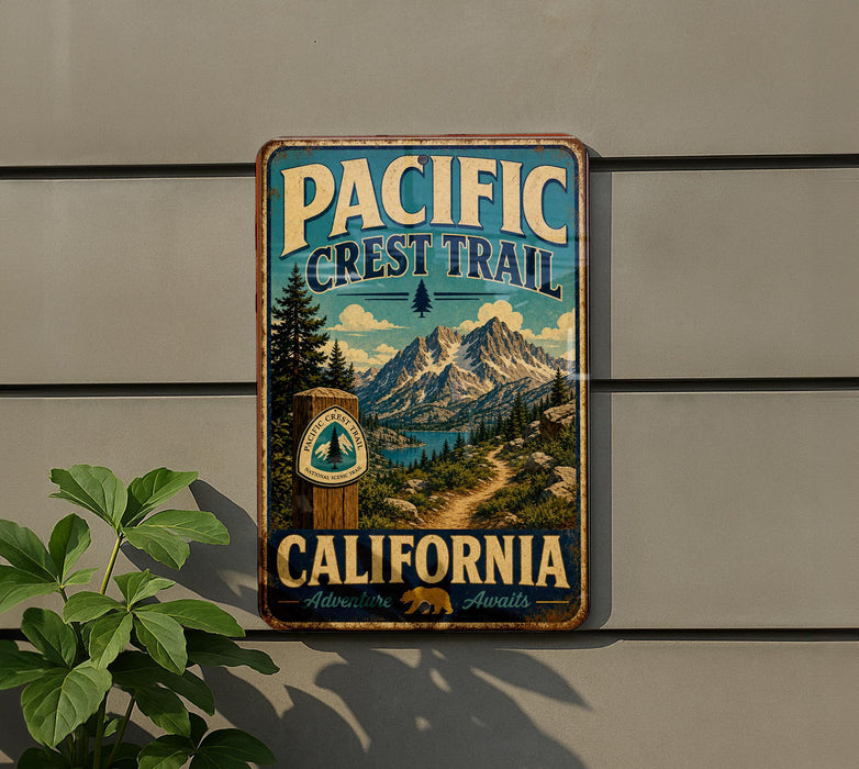 A vintage-style metal sign for the Pacific Crest Trail in California, featuring a scenic mountain landscape and a trail marker.
