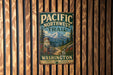 A vintage metal sign for the Pacific Northwest Trail in Washington, featuring a mountain landscape and the trail name.