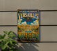 A vintage metal sign advertising the Palace and Park of Versailles in France, featuring an illustration of the palace and its gardens.