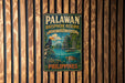 A vintage-style metal sign for the Palawan Biosphere Reserve, featuring a tropical landscape with a bird, a boat, and a tropical island.