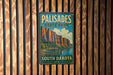 A vintage metal sign for Palisades State Park in South Dakota, featuring a scenic mountain landscape.
