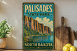 A vintage-style sign for Palisades State Park in South Dakota, featuring a scenic mountain landscape with a lake in the background.