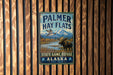 A vintage metal sign for Palmer Hay Flats, a state game refuge in Alaska, with a moose and a bird in the background.
