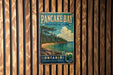 A vintage-style metal sign for Pancake Bay Provincial Park in Ontario, Canada, featuring a scenic landscape with pine trees, a beach, and a lake.