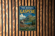 A vintage-style metal sign for the Gaspesie National Park in Quebec, featuring a reindeer and a mountain landscape.
