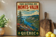 A vintage-style poster of the Monts-Valin National Park in Quebec, Canada, featuring a scenic mountain landscape with a river and pine trees.