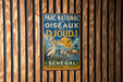 A vintage metal sign with text and illustrations, hanging on a wooden wall.