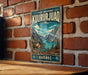 A vintage metal sign displaying the name "KUURURJUQA" and the location "QUÉBEC" is mounted on a brick wall.