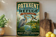 A vintage-style metal sign with a bird illustration and text, placed on a wooden surface next to a wooden cutting board and some lemons.