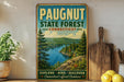 A vintage-style metal sign for Paugnut State Forest in Connecticut, featuring a scenic landscape with pine trees, a river, and mountains.