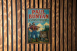 A vintage Paul Bunyan sign advertising a state forest in Minnesota, featuring a woodcut illustration of a lumberjack holding a chainsaw and standing in front of a sign that reads "Big Lakes Tall Pines Wildplains".