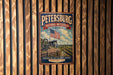 A vintage-style metal sign for the Petersburg National Battlefield in Virginia, featuring an American flag and a cannon, mounted on a wooden wall.