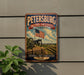 A vintage metal sign for the Petersburg National Battlefield in Virginia, featuring an American flag and a cannon, mounted on a wall.