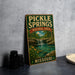 A vintage-style metal sign for Pickle Springs Natural Area in Missouri, featuring a scenic landscape with a waterfall and greenery.