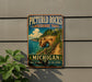 A vintage-style metal sign for the Pictured Rocks Lakeside Trail in Michigan, featuring a scenic landscape with a cliff, lake, and forest.