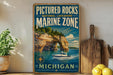 A framed poster of a boat on a lake, with the text "PICTURED ROCKS NATIONAL LAKESHORE MARINE ZONE MICHIGAN" and a scenic image of a lake with a boat.