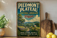 A vintage-style metal sign for Piedmont Plateau, Virginia, featuring a scenic landscape with a path, trees, and a house.