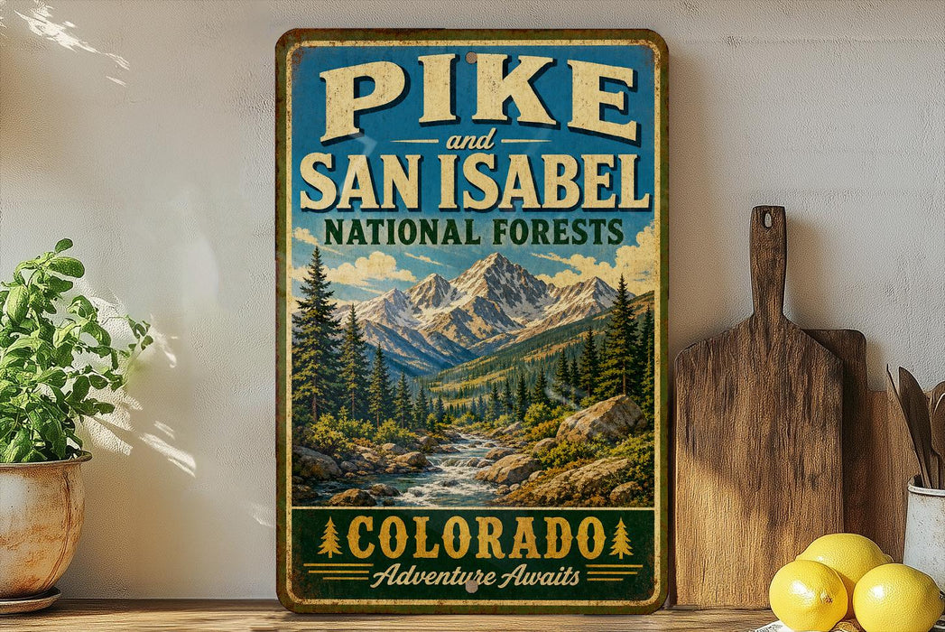 A vintage-style sign for the Pikes and San Isabel National Forests in Colorado, featuring a scenic mountain landscape with pine trees and a river.