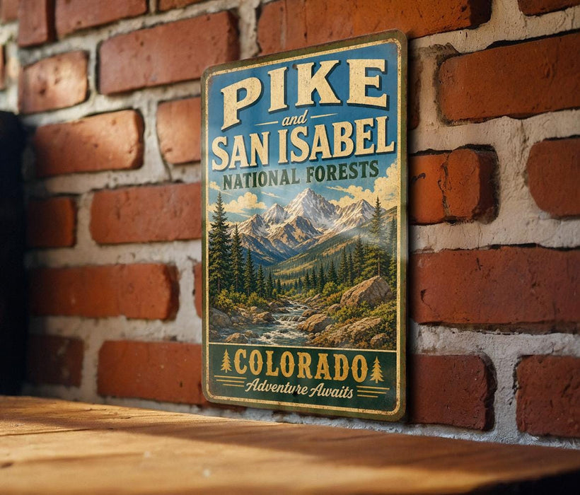 A vintage-style metal sign with the text "Pike and San Isabel National Forests" and "Colorado Adventure Awaits" is displayed on a brick wall.