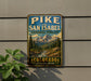 A vintage-style metal sign with a mountain landscape and a river, mounted on a wall.
