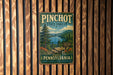 A vintage metal sign for Pinchot State Forest, featuring a scenic image of a forest and a lake, mounted on a wooden wall.