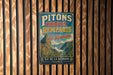 A vintage metal sign with text and an illustration of a mountainous landscape, mounted on a wooden wall.