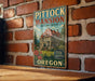 A vintage-style metal sign for the Pittock mansion in Portland, Oregon, featuring an illustration of the mansion and the text "Pittock Mansion Portland, Oregon" and "OREGON".