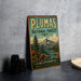 A vintage-style metal sign for the Plumas National Forest in California, featuring a scenic landscape with mountains, pine trees, and a river.
