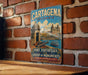 A vintage metal sign for Cartagena, Colombia, featuring an illustration of the city's landmarks and a boat on the water.