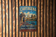 A vintage metal sign for Cartagena, Colombia, featuring a colorful illustration of the city's landmarks and a boat on the water.