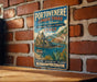 A vintage-style metal sign for Portovenere and the Cinque Terre in Italy, featuring a castle, a boat, and a scenic view of the islands.