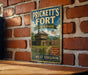 A vintage metal sign for Prickett's Fort, a historic attraction in West Virginia, is displayed on a brick wall.