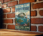 A vintage-style sign for the Protection Island Aquatic Reserve in Washington, featuring a fish, a lighthouse, and a boat, mounted on a brick wall.