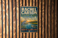 A vintage-style metal sign for Rachel Carson Estuarine Reserve in North Carolina, featuring an illustration of a bird and a turtle in a natural setting.