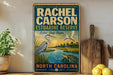 a vintage-style sign for Rachel Carson Estuarine Reserve in North Carolina, with illustrations of birds and a turtle.