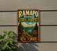 A vintage metal sign for Ramapo Mountain State Forest in New Jersey, featuring a scenic landscape with pine trees, mountains, and a lake.