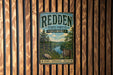 A vintage metal sign for the Redden State Forest in Delaware, featuring a scenic image of a forest and a river.