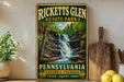 A vintage-style metal sign for Rickeett's Glen State Park in Pennsylvania, featuring a scenic waterfall surrounded by lush greenery.