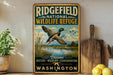 A vintage-style metal sign for the Ridgefield National Wildlife Refuge in Washington, featuring a duck in flight and a scenic landscape.