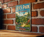 A vintage-style metal sign for Ries Park, Germany, featuring a scenic landscape with a bridge and trees, mounted on a brick wall.