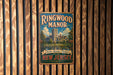 A vintage-style metal sign for Ringwood Manor, featuring a castle and trees, is displayed on a wooden wall.