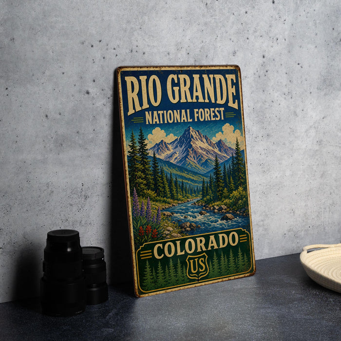A vintage-style sign for the National Forest in Colorado, featuring a mountain landscape with pine trees and a river.