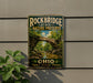 A vintage-style metal sign for Rockbridge State Nature Preserve, featuring a scenic image of a stone bridge surrounded by lush greenery.