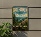 A vintage-style metal sign for Rothrock State Forest in Pennsylvania, featuring a scenic mountain landscape with pine trees and a river.