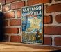 A vintage metal sign on a brick wall, displaying a map of the Routes of Santiago de Compostela in France, with a person holding a walking stick and a map of the region.