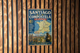 A vintage metal sign on a wooden wall, advertising the Routes of Santiago de Compostela in France.