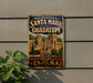 A vintage metal sign with the text "REAL MONASTERIO DE SANTA MARIA DE GUADALUPE ESPAÑA" and an illustration of a castle, with the word "ESPAÑA" below it.