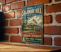 A vintage-style sign for Sagamore Hill, New York, featuring an illustration of a house and the text "Welcome to Sagamore Hill" and "Home of Theodore Roosevelt".