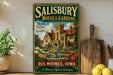 A vintage-style metal sign for Salisbury House & Gardens in Des Moines, Iowa, featuring a castle-like building surrounded by gardens and a fountain.
